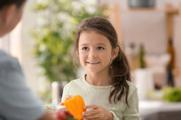 Fototapeta premium Little girl with her mother cooking together in kitchen