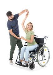 Beautiful woman in wheelchair with man dancing on white background