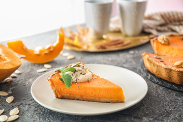 Plate with piece of tasty pumpkin pie on table