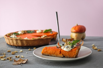 Plate with piece of tasty pumpkin pie on table