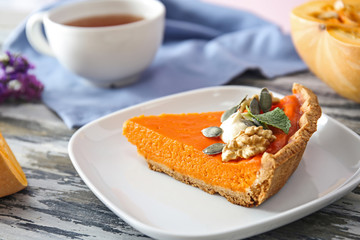Plate with piece of tasty pumpkin pie on wooden table, closeup