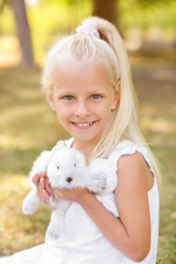 Little girl with cute rabbit outdoors