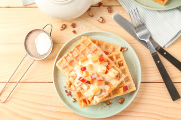 Delicious waffles with peach on wooden table