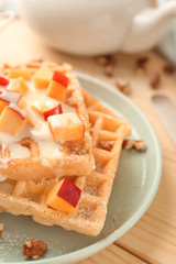 Delicious waffles with peach on plate