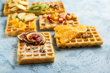 Delicious waffles with fruits on color table