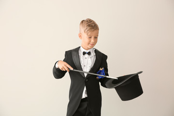 Cute little magician showing trick with hat on white background