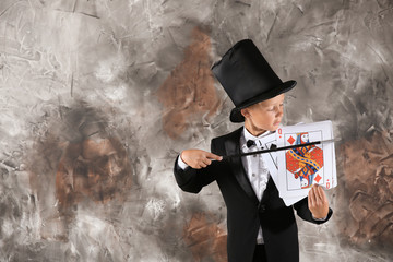 Cute little magician showing trick with cards on grunge background