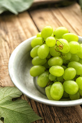 Bowl with sweet grapes on wooden table