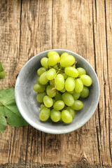 Bowl with sweet grapes on wooden table