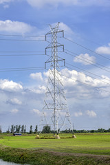 Electrical power line on green grass and blue sky.