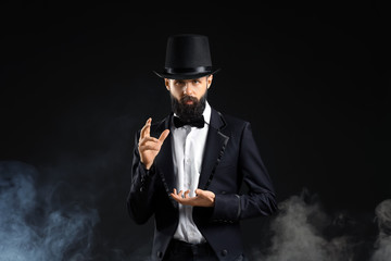 Magician showing tricks in smoke on dark background