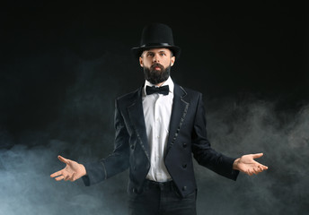 Magician showing tricks in smoke on dark background