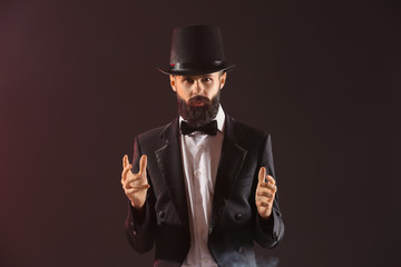 Male magician on dark color background