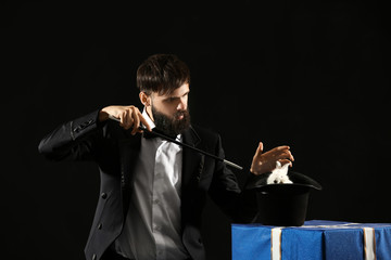 Magician showing tricks with rabbit on dark background