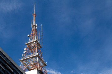 Bellow view of a giant television antenna/tower with a blue sky in the background. Communication, engineering and technology as a concept
