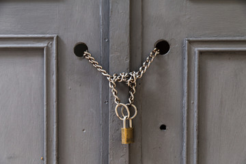 A front view of a door locked with chains and a padlock. Building and security as a concept