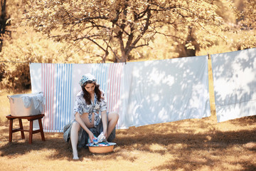 Fototapeta premium Pregnant woman hanging sheets on the rope for drying