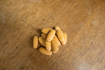 Orange multivitamin dietary supplement tablets on wood