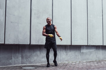 Fight right now! Full length of young man in sportswear exercising against grey background outdoors