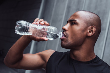 Naklejka na ściany i meble Perfect drink is always water. Portrait of handsome young man in sportswear drinking water