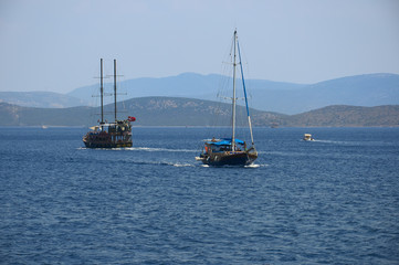 Fototapeta na wymiar Water excursion in Turkey. Two ships diverge in the Sea. Blue sea and. Coast of the Aegean Sea. Turgutreis , Bodrum.mountains.