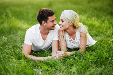 The lovely couple in love sitting on green grass.