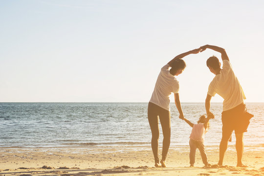 Selective focus Happy family with little girl play at sunset beach.Happy Asian family outdoor activity, holding hands together walking on sand seaside in sunset during vacations.