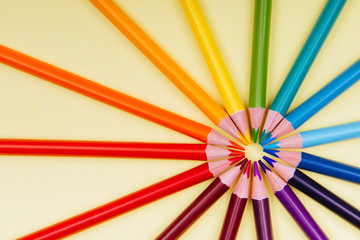 Fototapeta premium Color pencils in a row on yellow background.