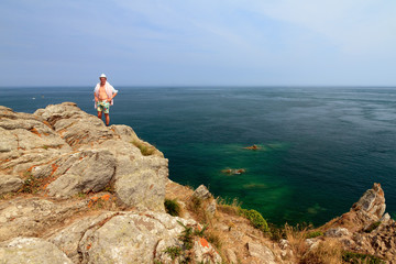 Obraz premium Beautiful view of a colorful young tourist on the rocks at Pointe du Grouin near Cancale in Brittany, France, in summer