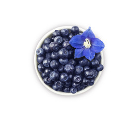 Top view. Bilberres and blue flower. Ripe blueberries with copy space for text. Ripe and tasty blueberries. Blueberries in a white ceramic bowl.