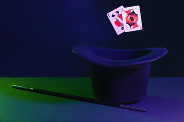 Black hat, magic wand and cards on dark background