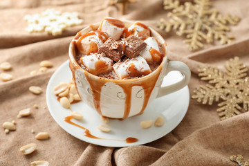 Cup of hot chocolate with marshmallows and caramel on napkin