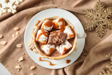 Cup of hot chocolate with marshmallows and caramel on napkin