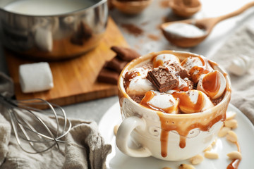 Cup of hot chocolate with marshmallows and caramel on table