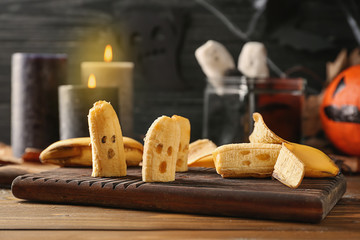 Creative bananas prepared for Halloween party on wooden board