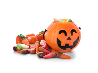 Basket in shape of pumpkin with candies for Halloween party on white background