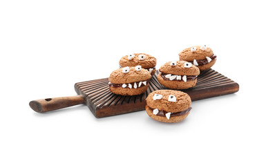 Wooden board with creative cookies prepared for Halloween party on white background