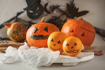 Creative oranges with pumpkins prepared for Halloween party on wooden board