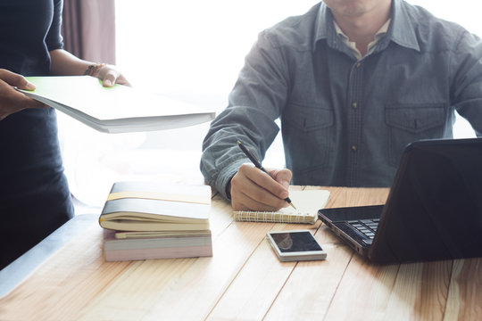 Business meeting time.People writing on notebook and work with mobile phone,books and laptop on wooden table - Powered by Adobe
