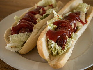 Hot dog with vegetables, ketchup and mustard on wooden table