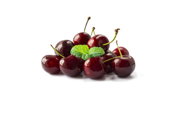 Fresh red cherries lay on white isolated background. Ripe cherry with a leaf of mint on a white background. Cherries with copy space for text.