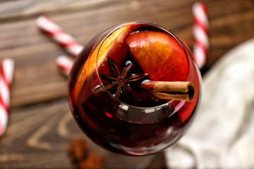 Glass of delicious mulled wine on wooden table, closeup