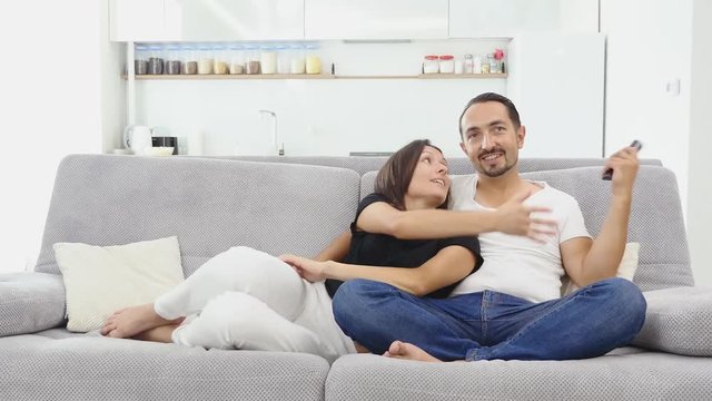 4K Couple fighting over the remote control in front of TV