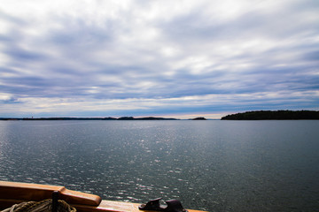 Looking starboard from a schooner towards the horizon of calm seas and cloudy skies, sailing from Turku to the Island of Aspö in Archipelago National Park (Skärgårdshavet nationalpark), Finland.