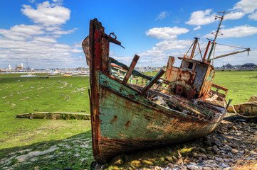 Old rusty fishing boat wreck on green dry land at low tide in the harbour of Larmor-Plage, Lorient,...