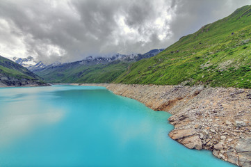 Beautiful view of reservoir lake Moiry (lac de Moiry) with vibrant turquoise blue water at a low level in summer in Valais, Switzerland