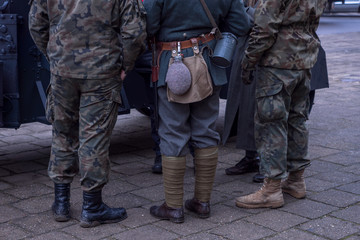 legs of soldiers from different eras. shoes, a flask for water, a knife.