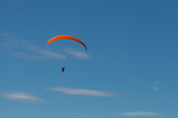 a man on a paraglider soars in the sky