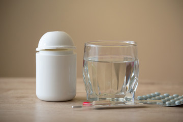 Glass of Water, Pills, Thermometer  on a Wooden Background. Copy Space. Medicine Concept Photo.