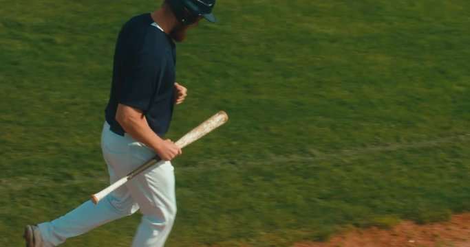 Batter baseball player running with a bat across the field. 4K UHD 60 FPS SLO MO RAW